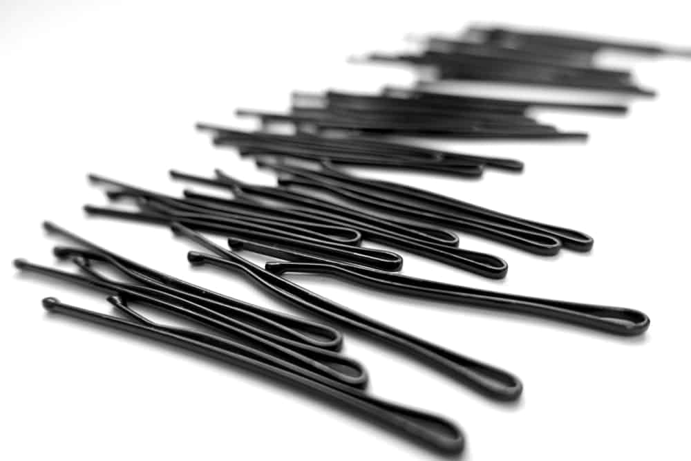 A close look at a bunch of bobby pins on a white surface.